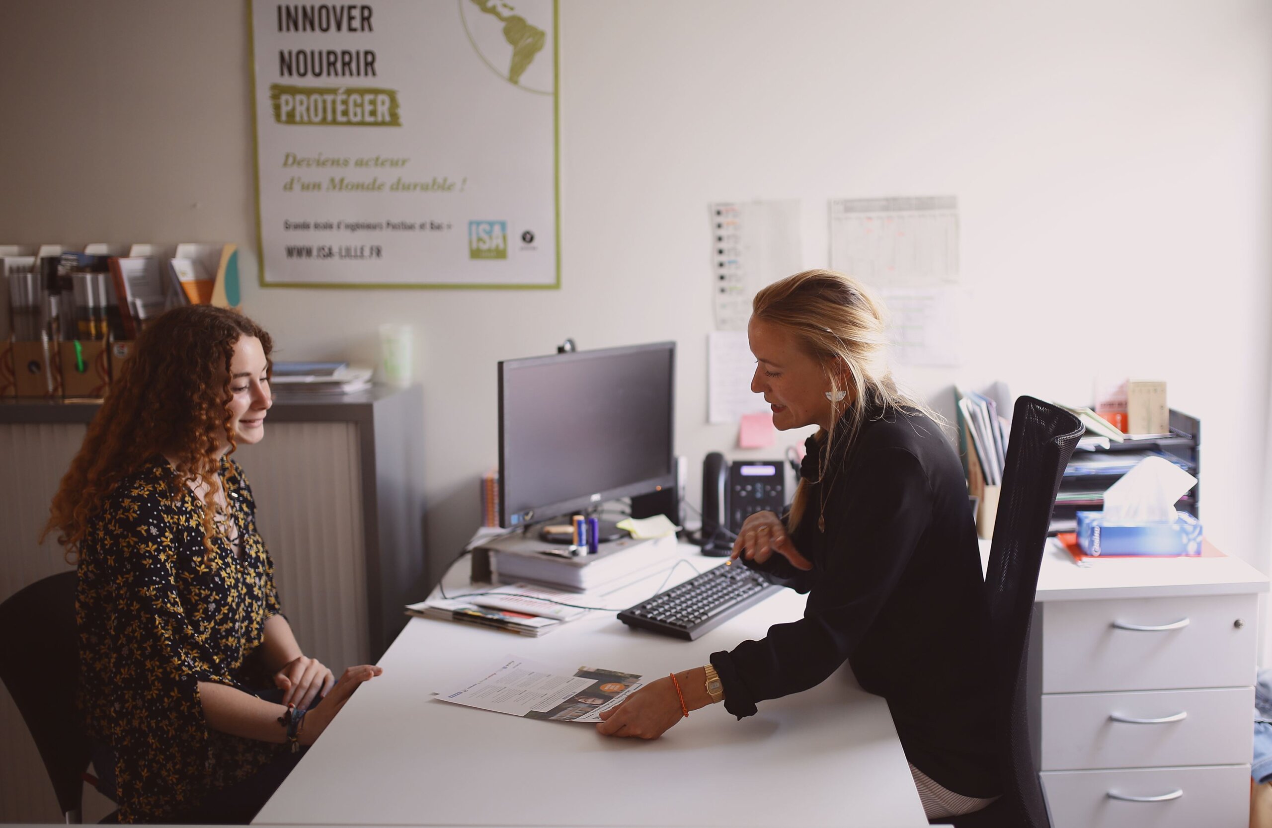 une étudiante assise derrière le bureau d'une salariée, en train de discuter