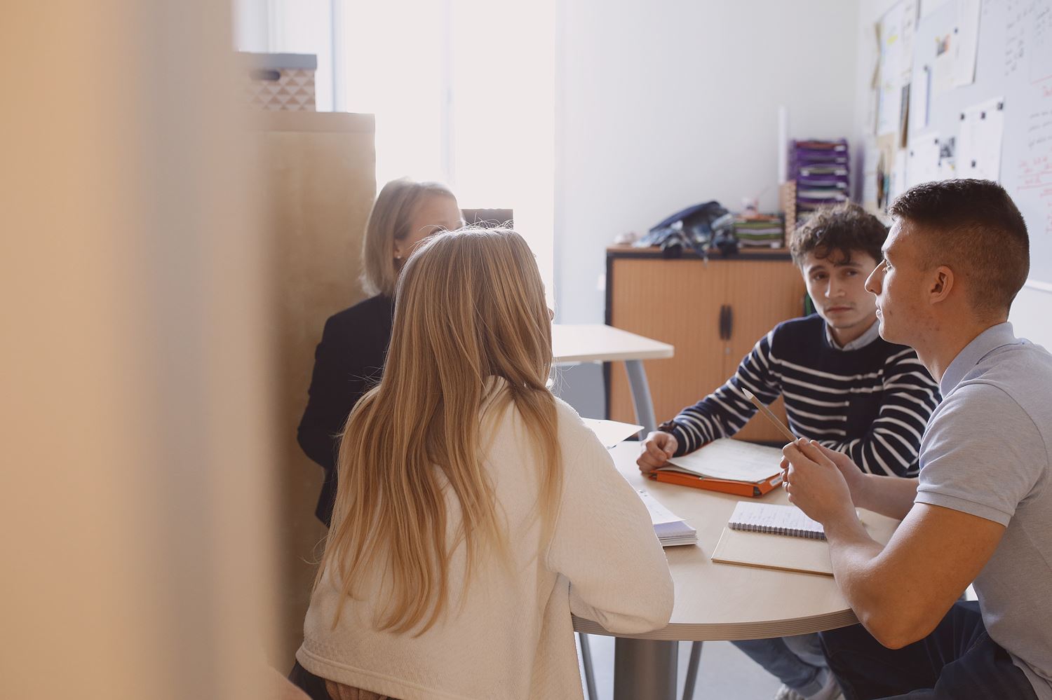 des étudiants assis autour d'une table avec une prifesseure