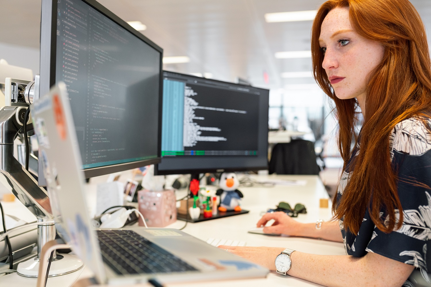 femme à son bureau devant plusieurs écrans