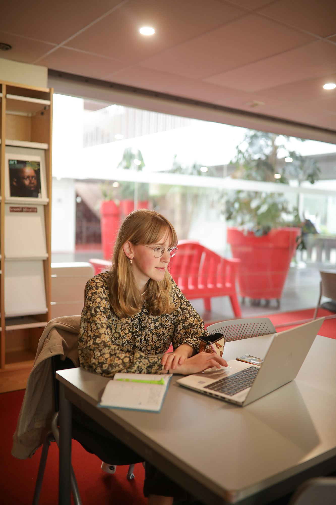 Une étudiante en train de travailler sur son ordinateur dans la bibliothèque