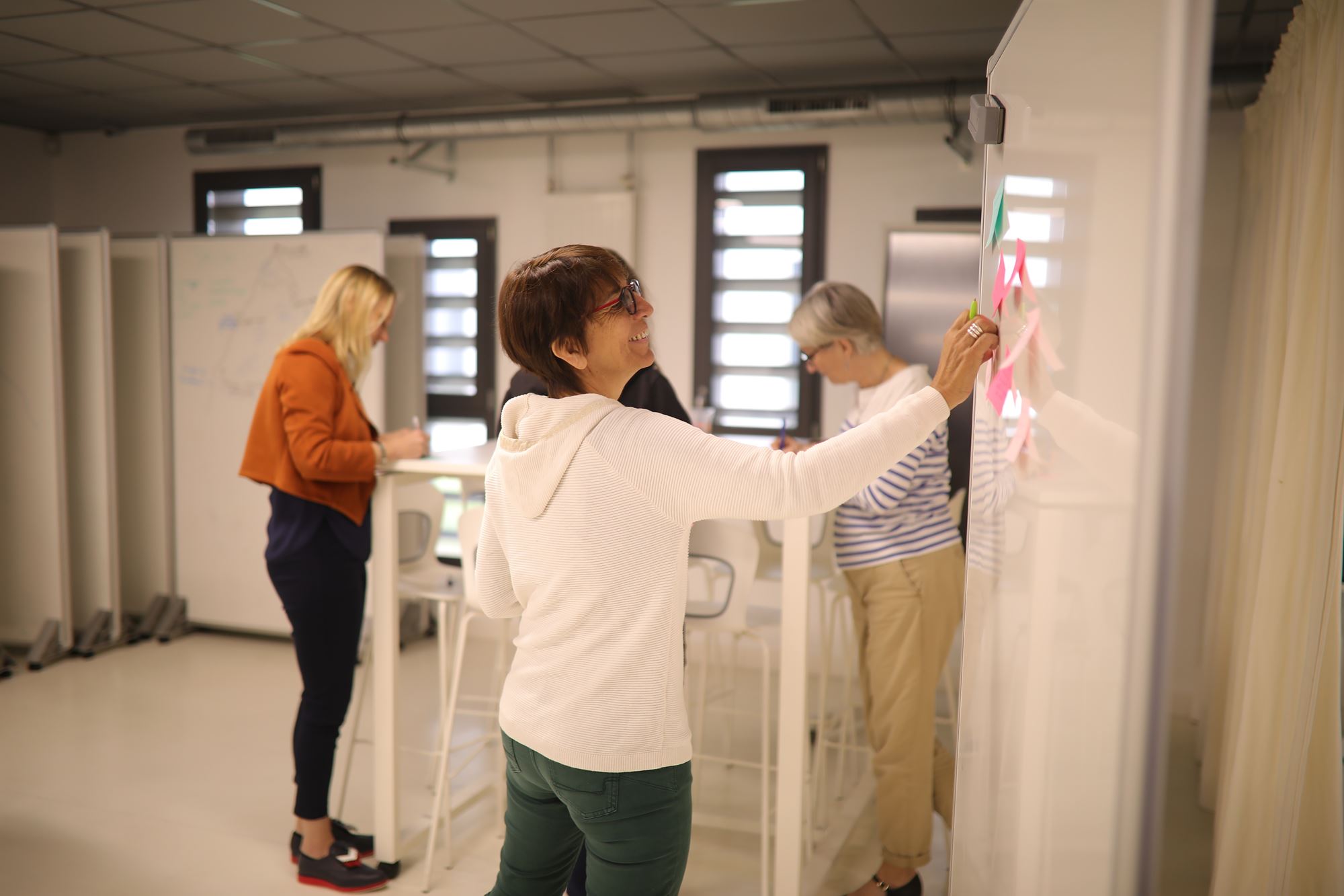 personnes collant des posts-it sur un tableau blanc