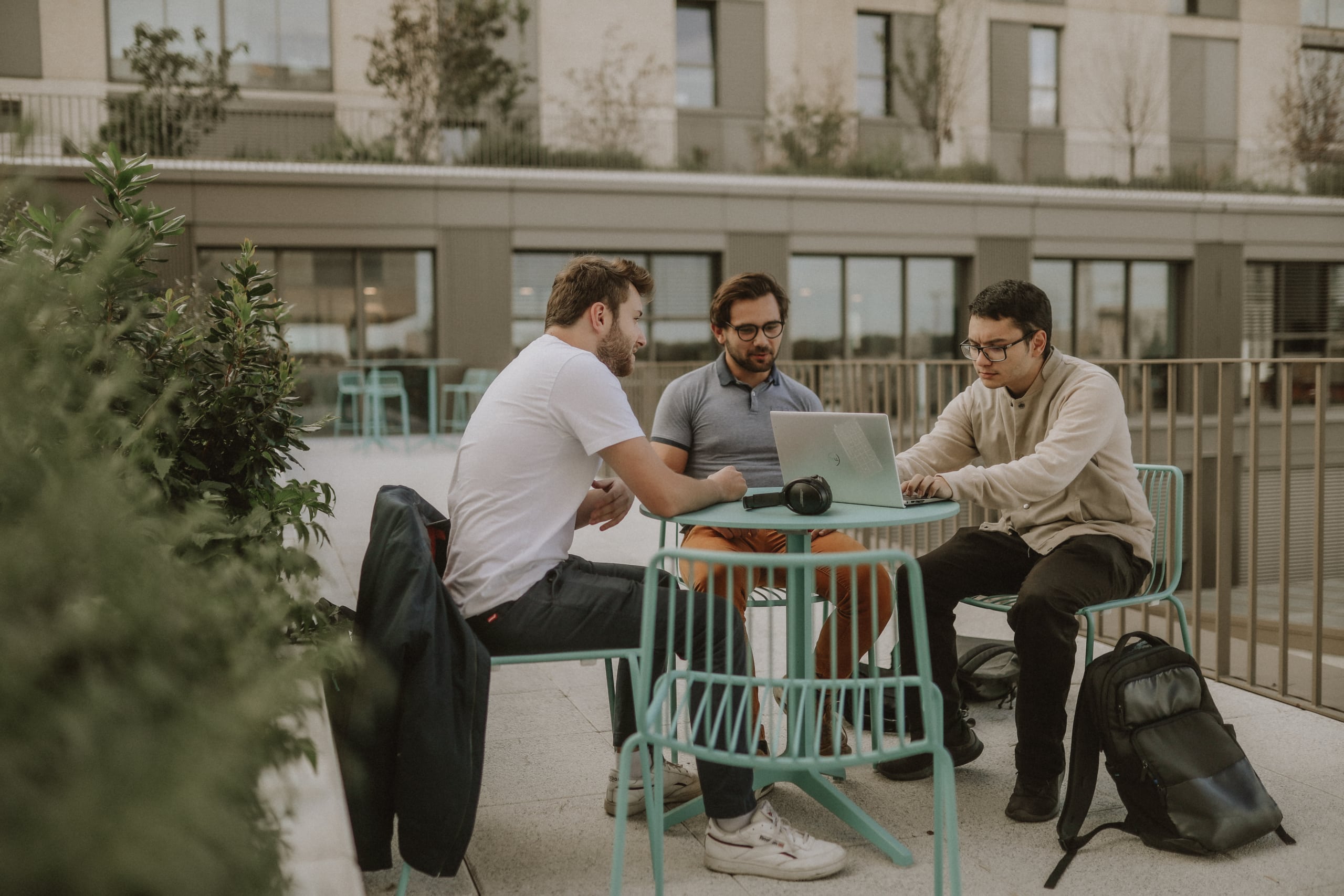 Trois étudiants travaillent en extérieur sur la terrasse du campus