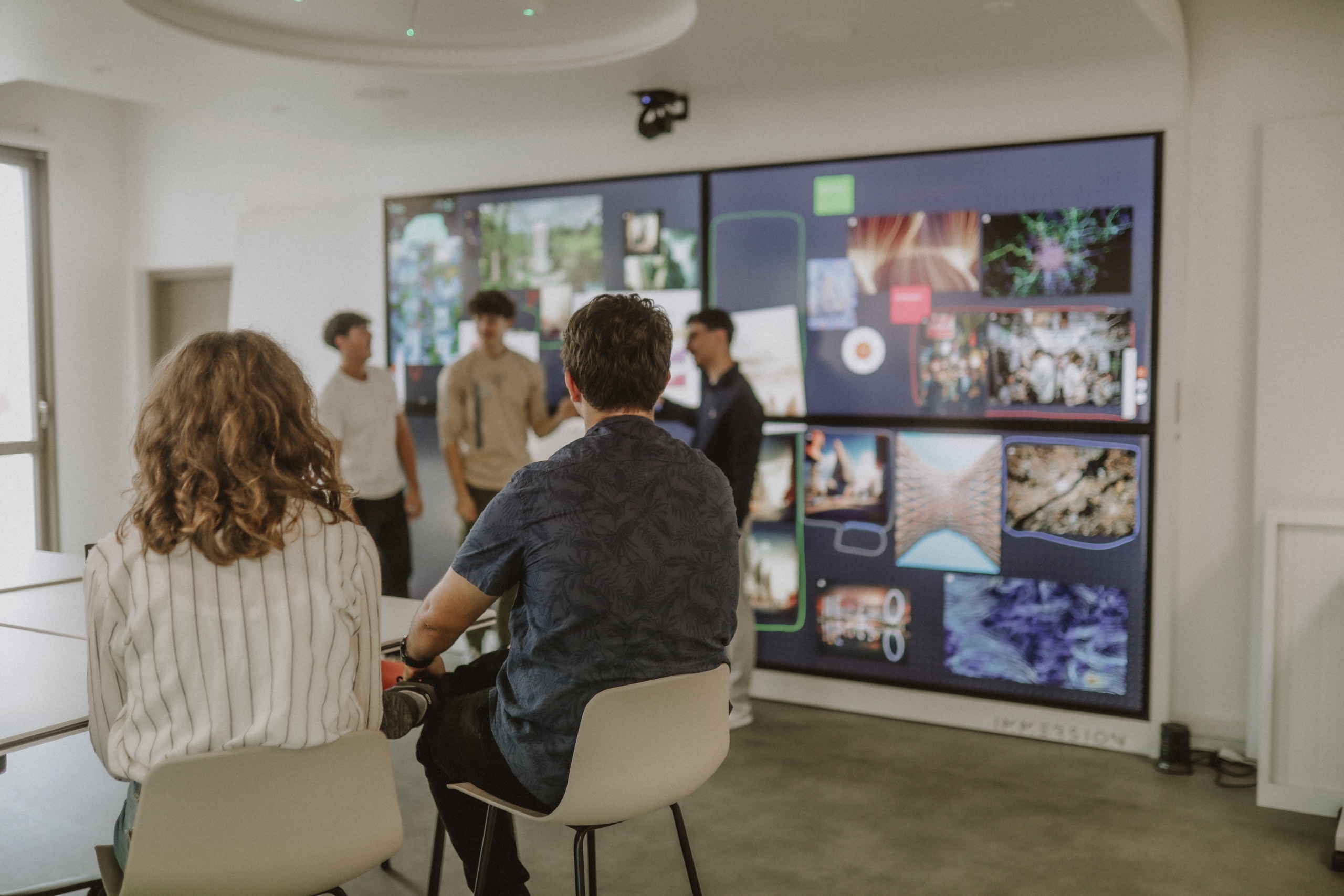 Des étudiants font une présentation sur l'écran tactile de la salle immersive du campus de Bordeaux