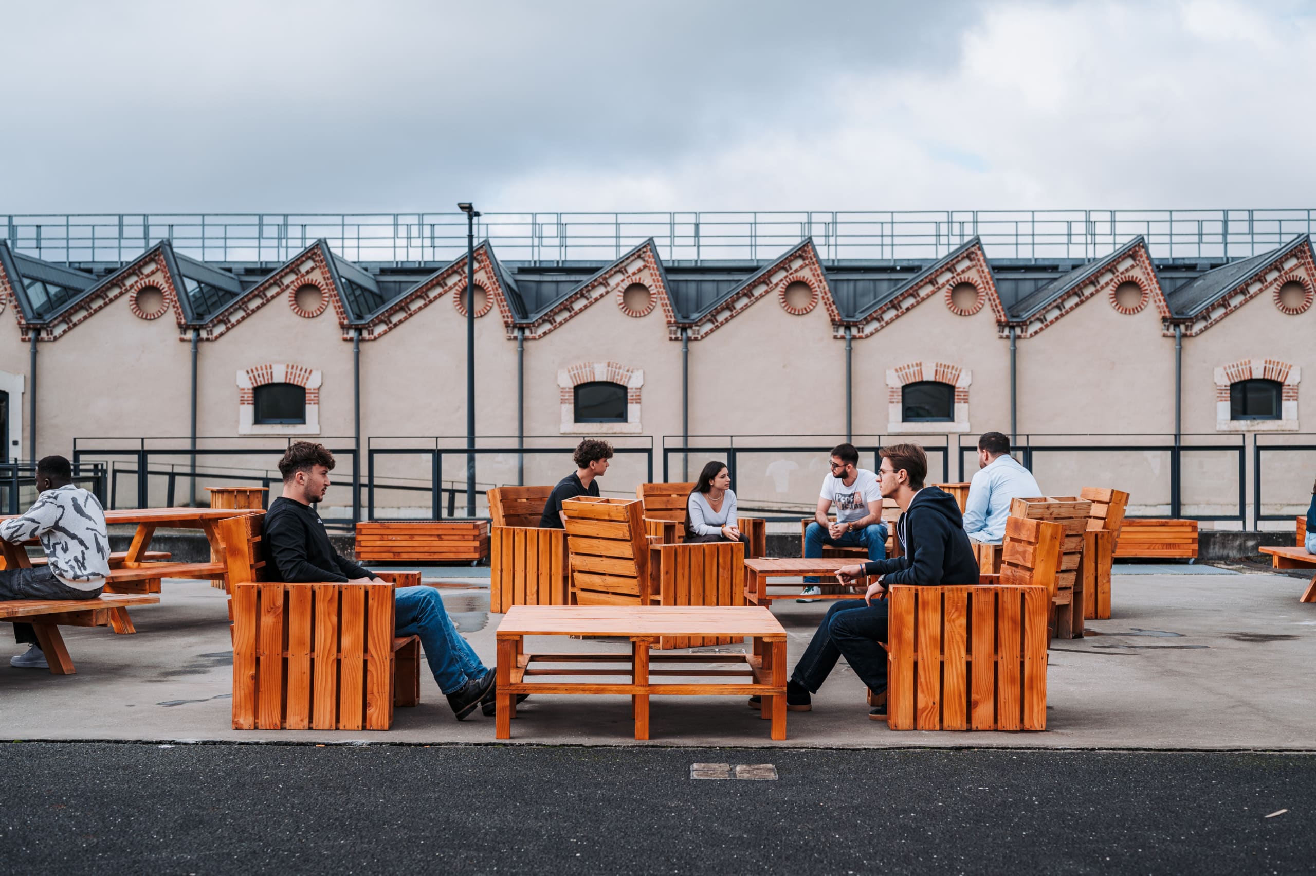 Des étudiants sur le mobilier en bois à l'extérieur du campus