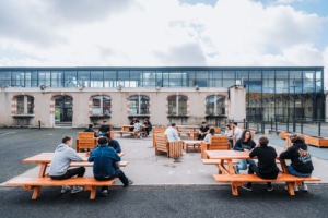Des étudiants sur le mobilier en bois à l'extérieur du campus