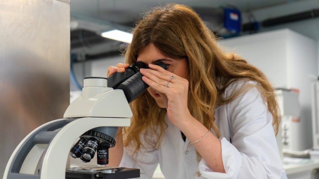 A teacher looks through a microscope