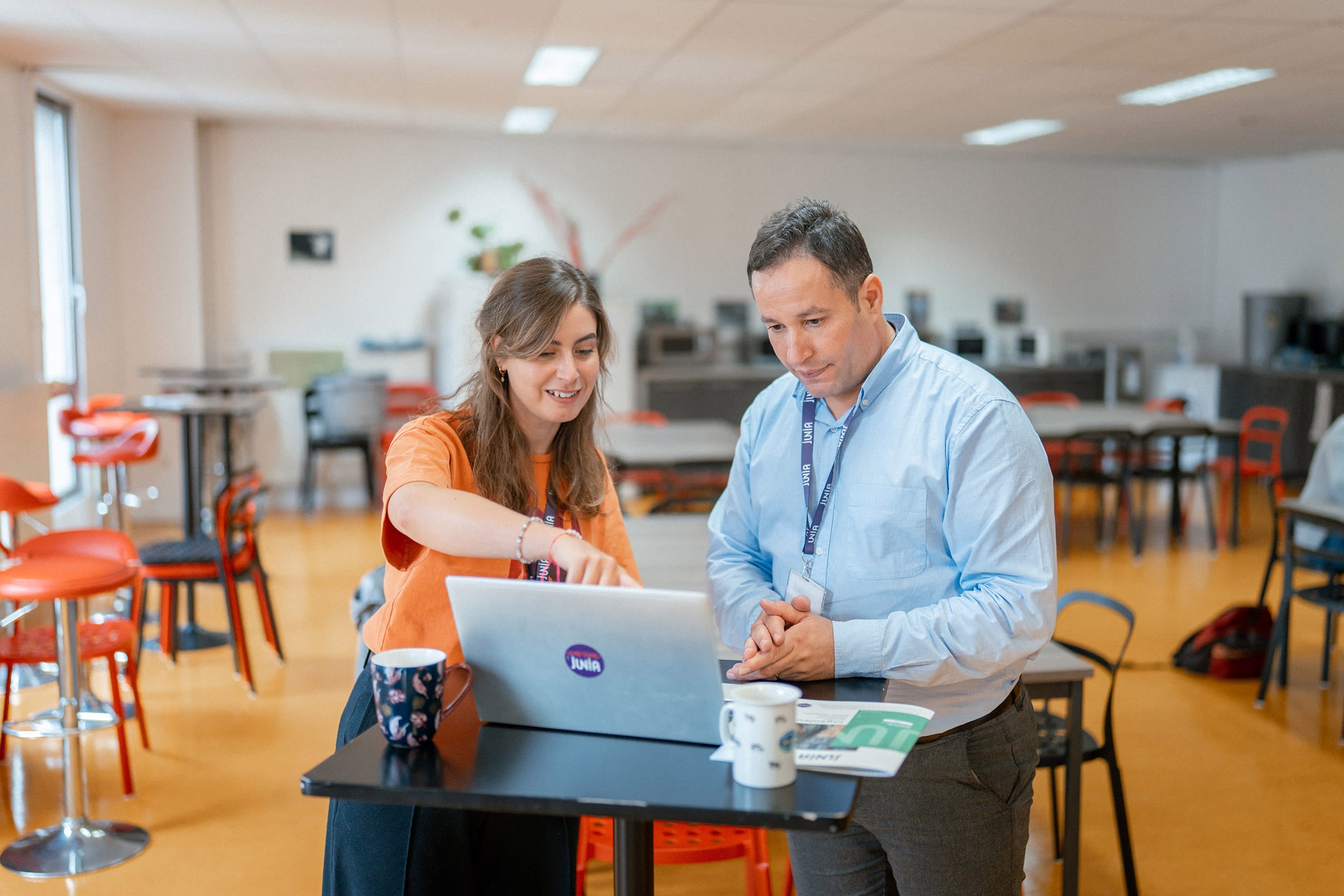 Two coworkers are talking in front of a computer