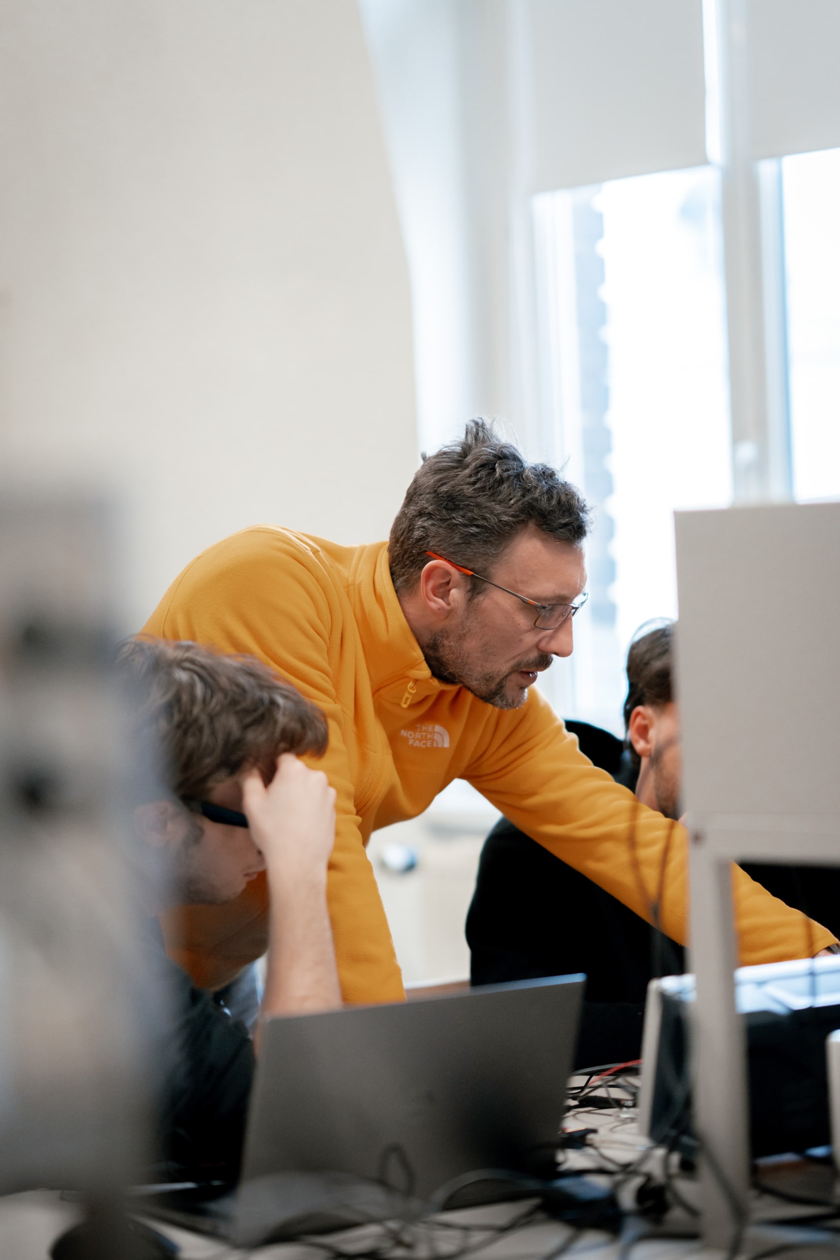 A teacher wearing a yellow sweater