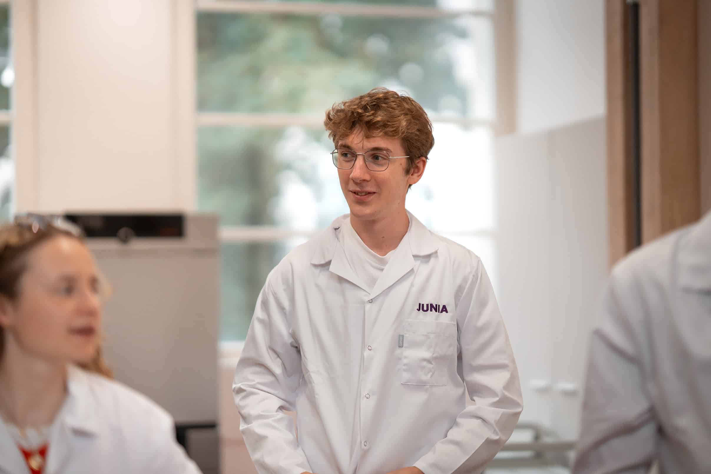 Un étudiant qui porte une blouse blanche floquée JUNIA
