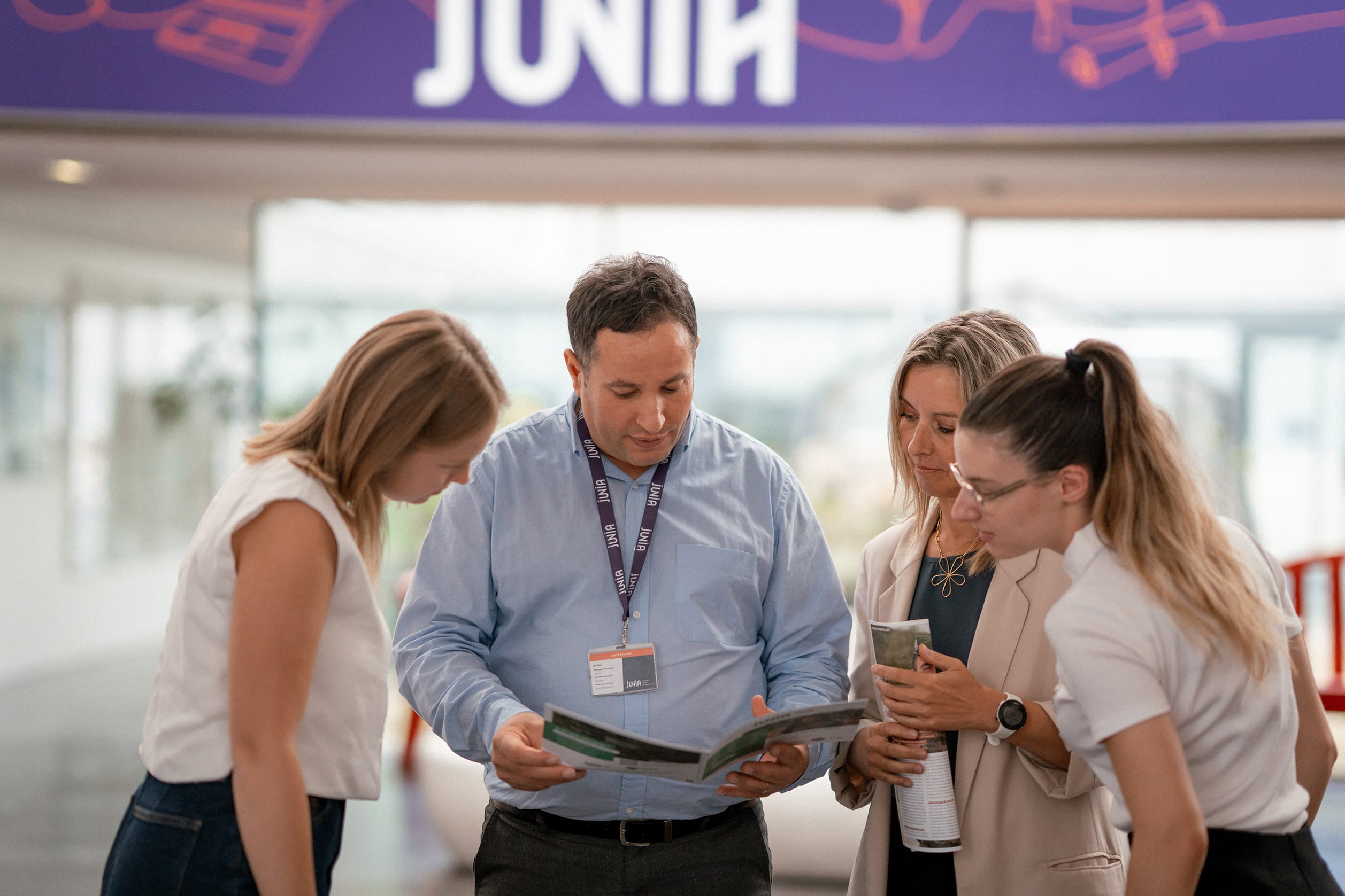 Groupe de collaborateurs se penchant sur une brochure dans le hall de JUNIA