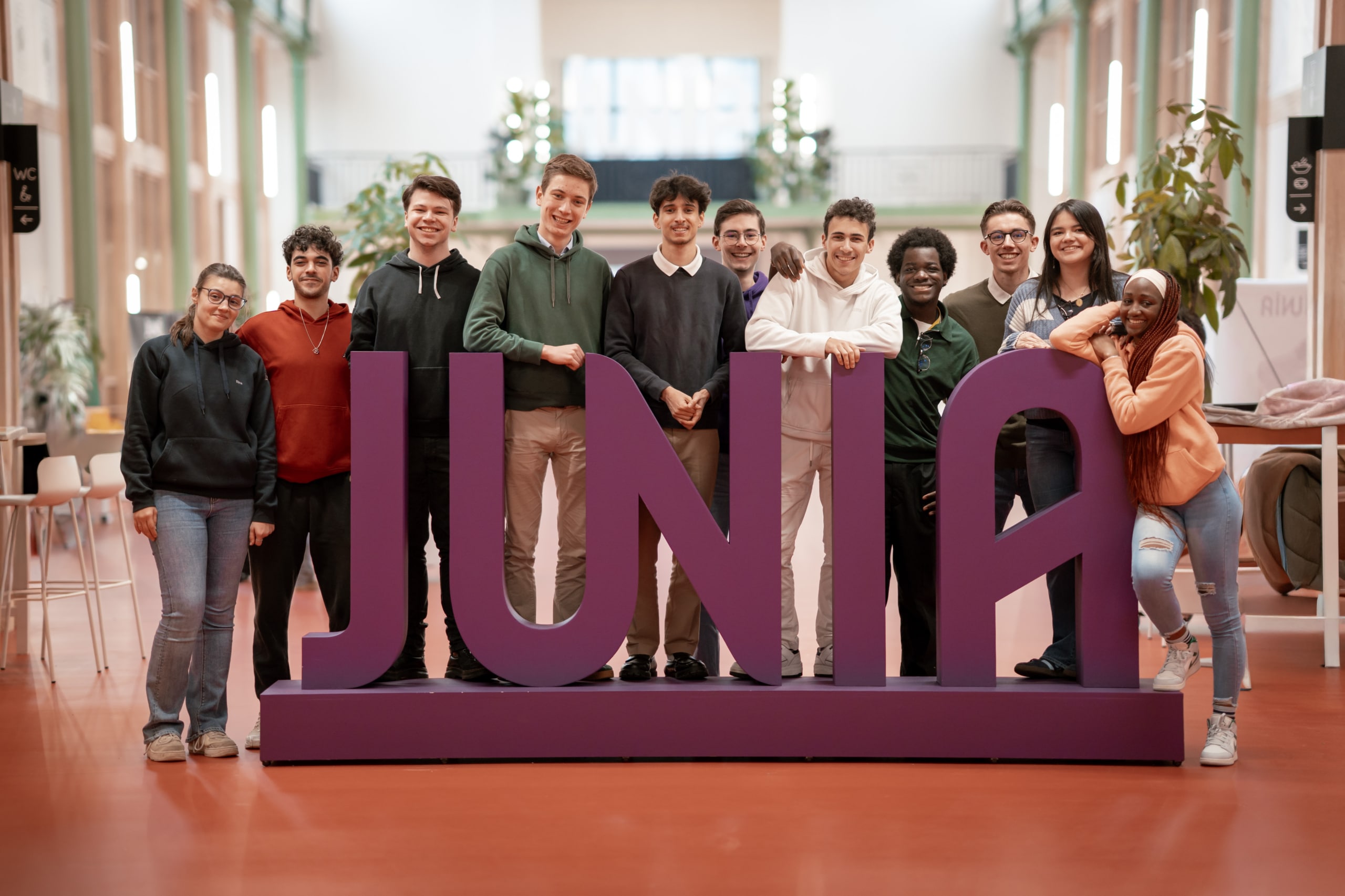 Un groupe d'étudiants prend la pose devant le logo JUNIA