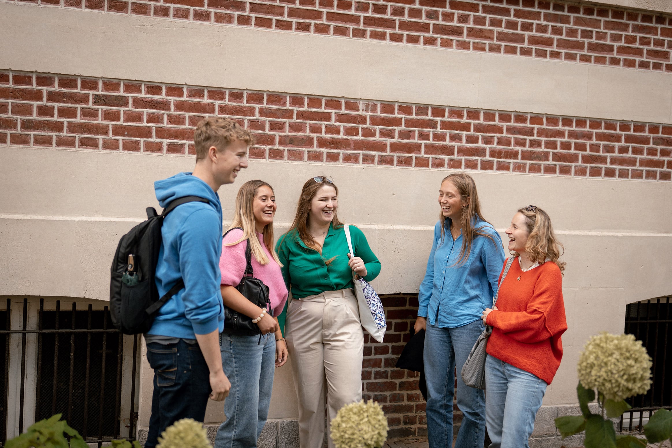 Un groupe d'étudiants discute, appuyé contre un mur